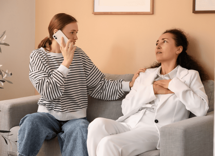 imagem mostra uma mulher ligando para a emergencia enquanto a outra está infartando