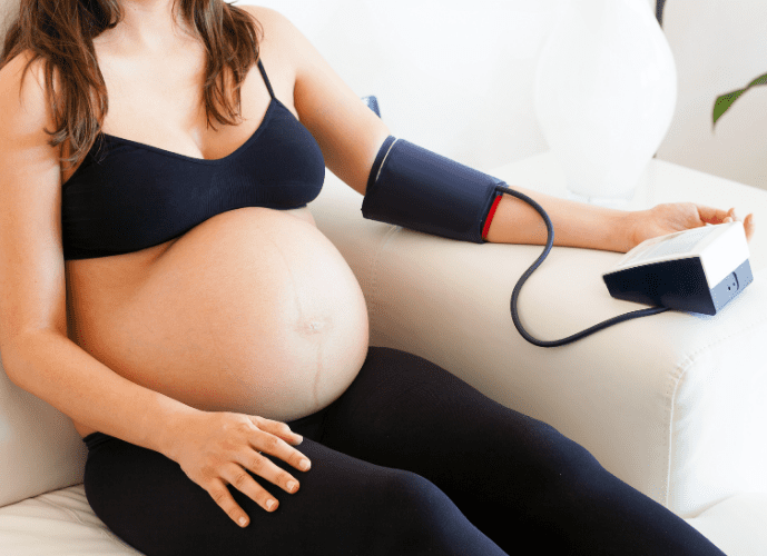 gravida sentada no sofá afereindo a pressão 